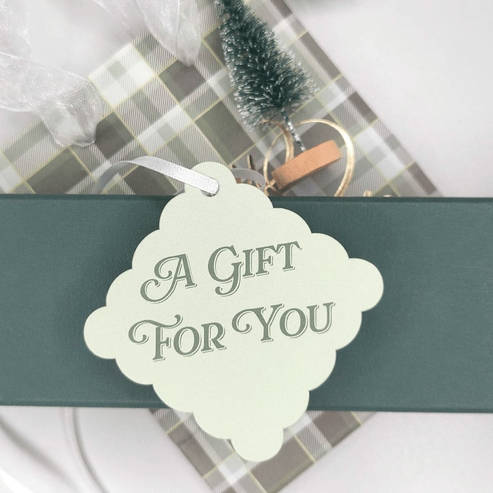 A light green holiday tag that reads "A Gift For You."